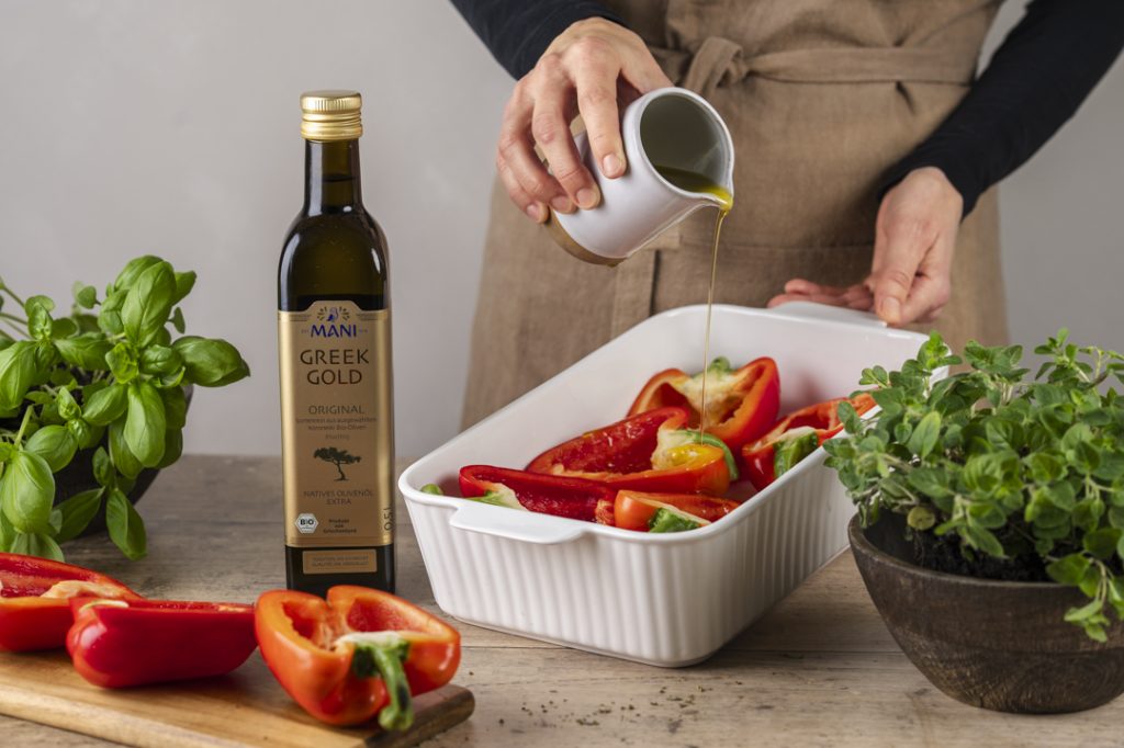 Greek Gold Olivenöl wird über Paprika in einer Auflaufform gegossen.